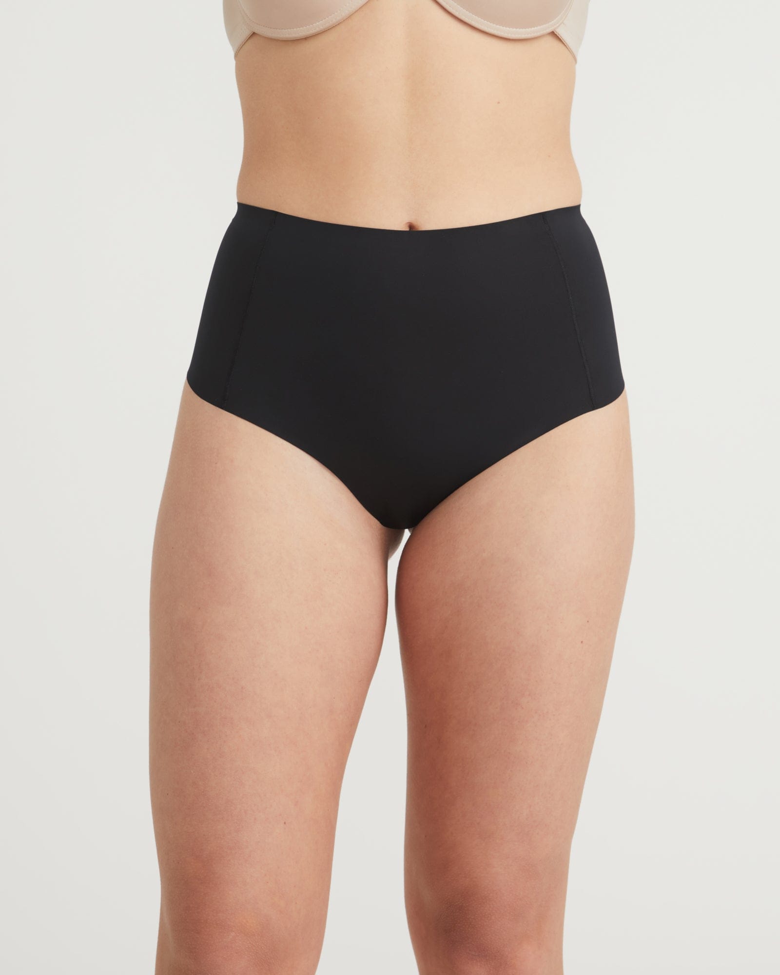 Person wearing black high-waisted underwear on a plain background