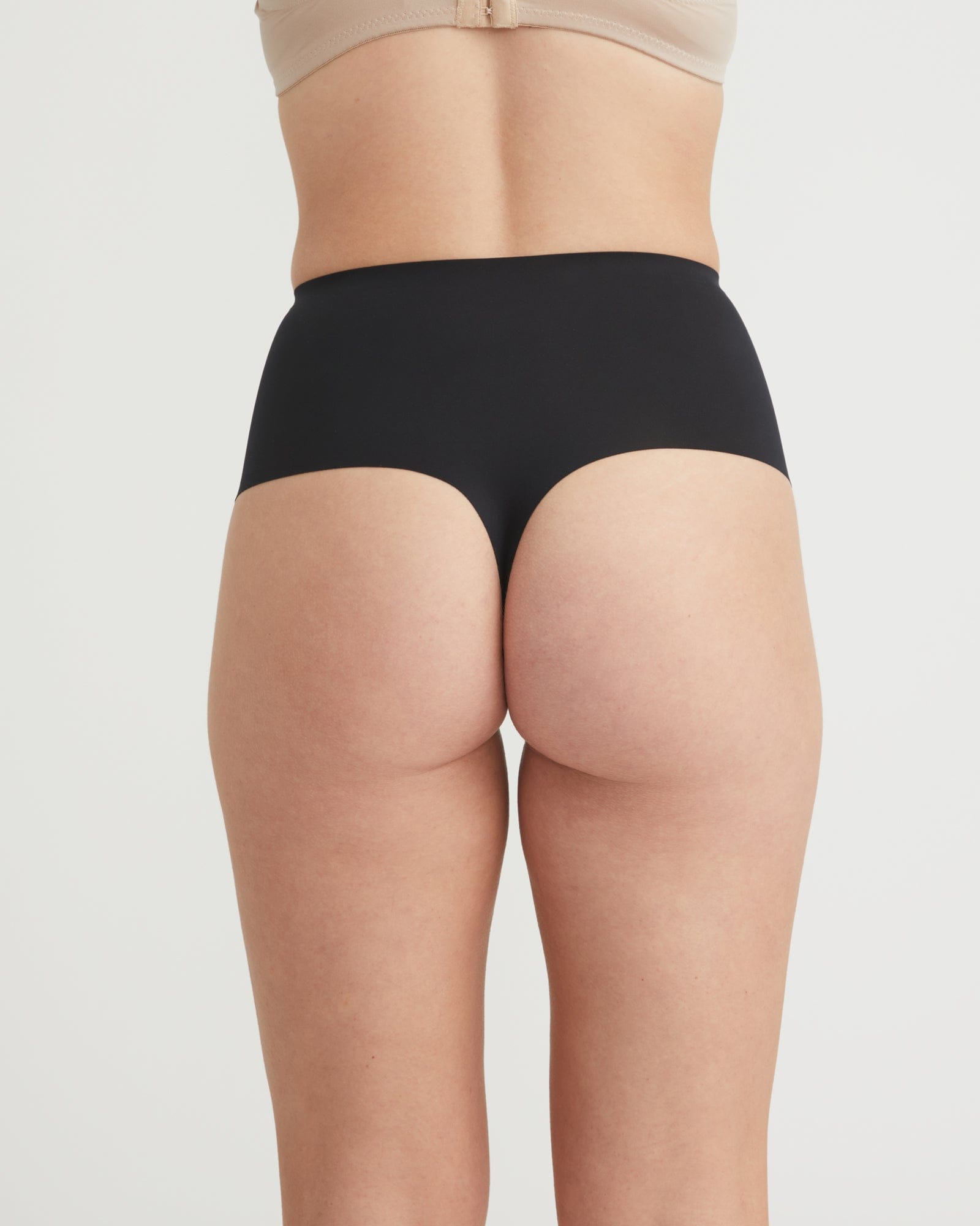 Black underwear worn by a person on a light gray background