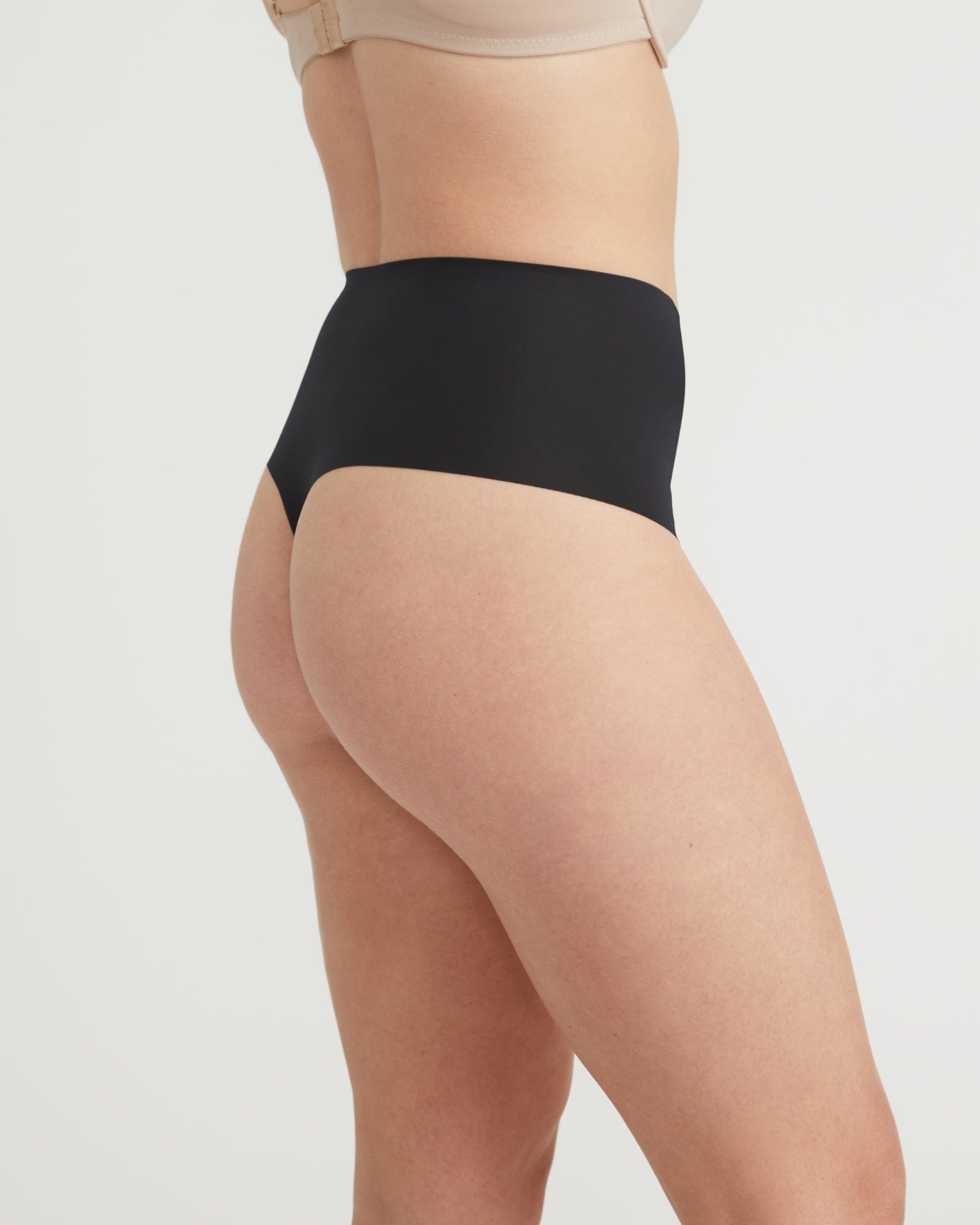 Person wearing black high-waisted underwear on a plain background