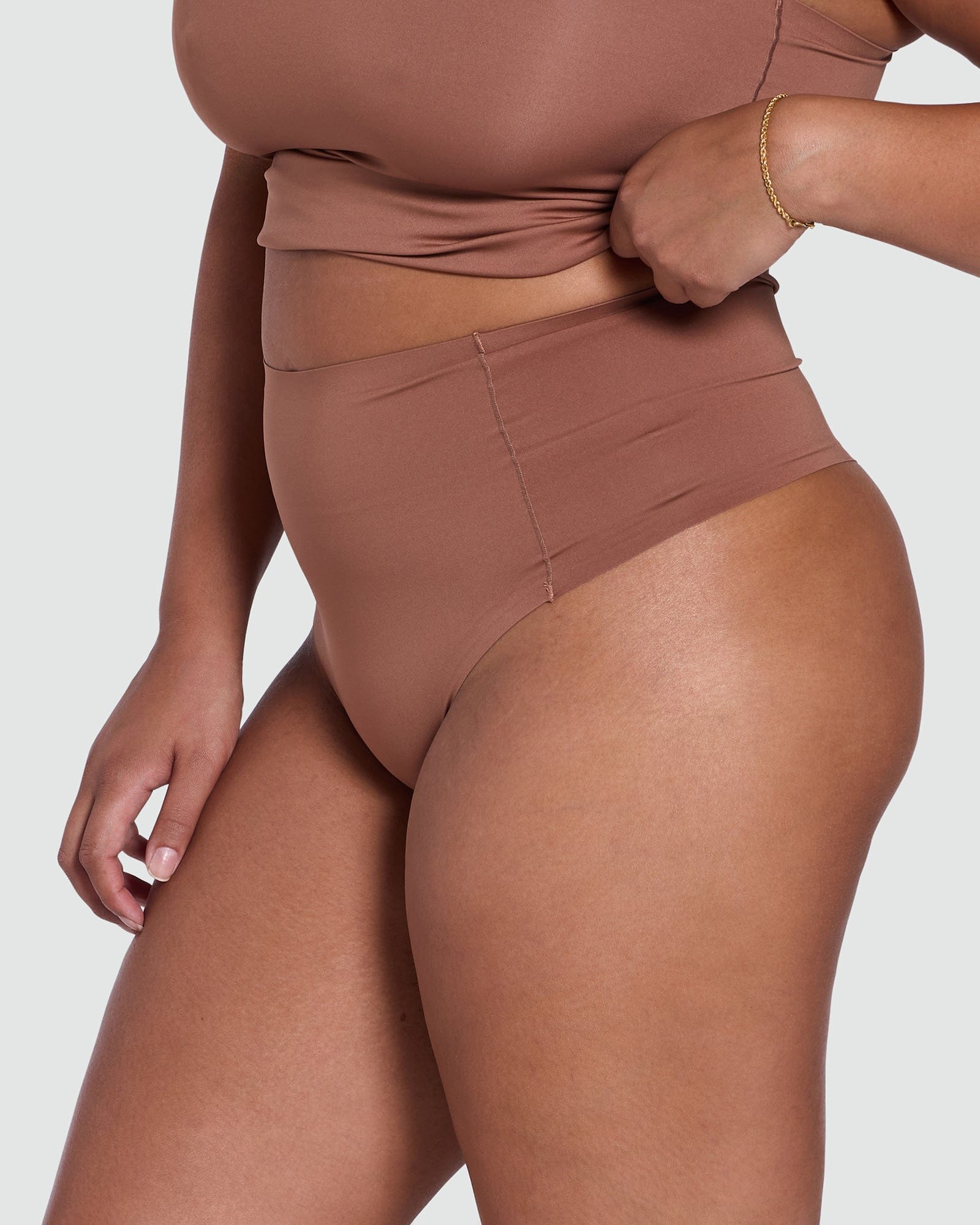 Person wearing a brown high-waisted bikini bottom on a white background