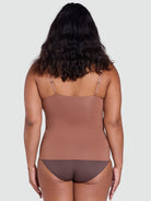 Woman wearing a brown bodysuit against a plain background
