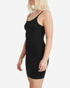 Black slip dress worn by a model on a white background