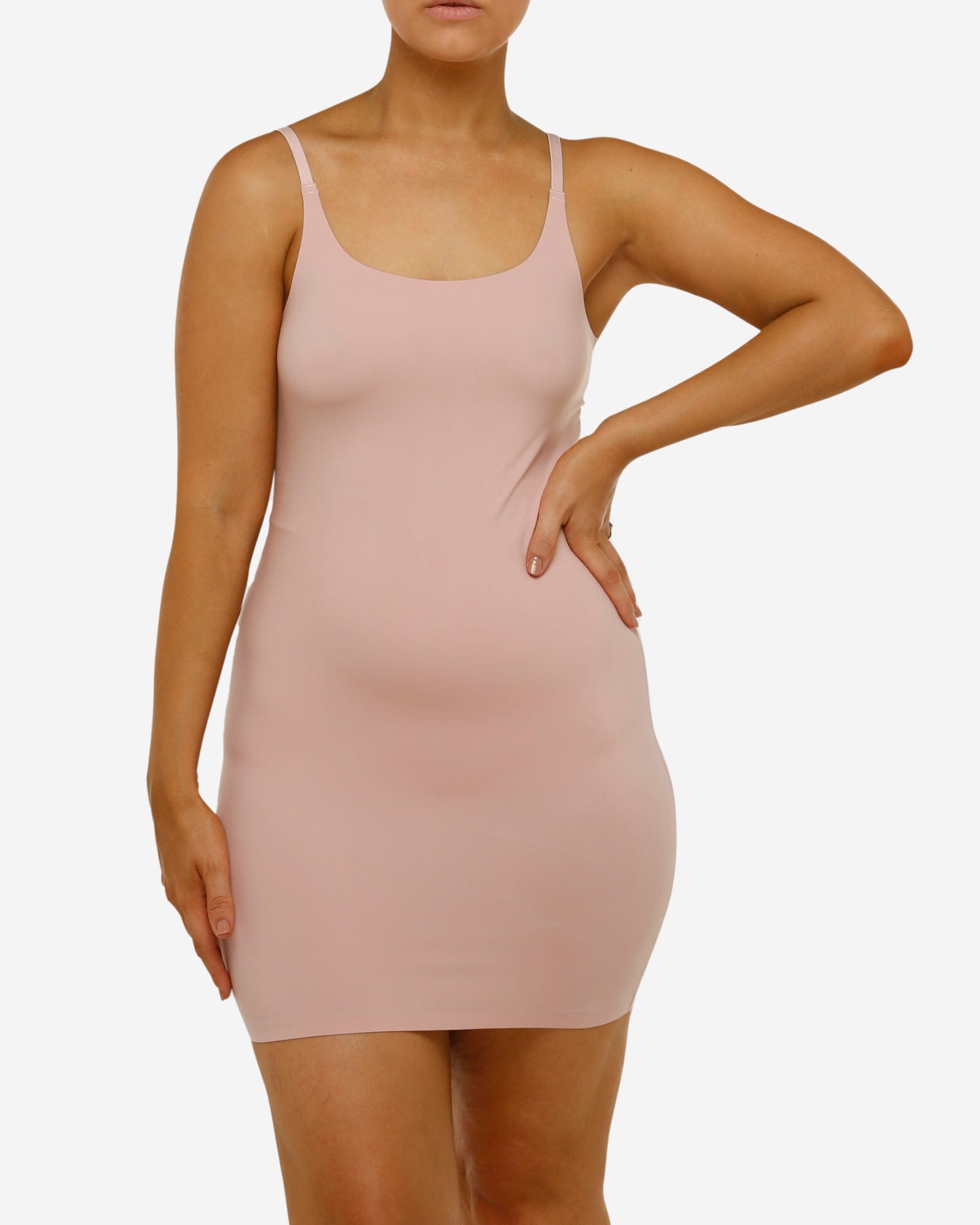 Woman wearing a light pink slip dress against a white background