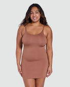 Woman wearing a brown slip dress against a plain background