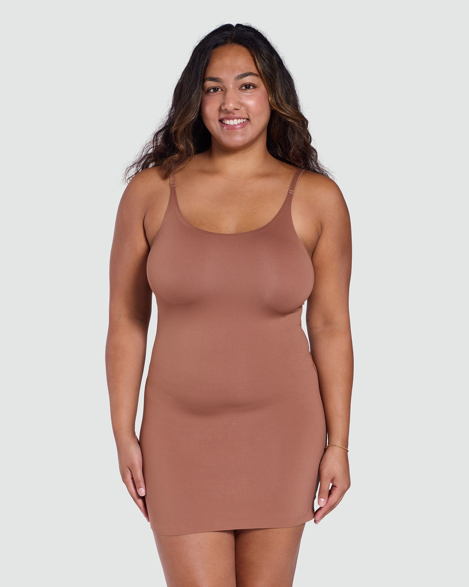 Woman wearing a brown slip dress against a plain background
