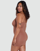 Woman wearing a brown bodysuit against a white background