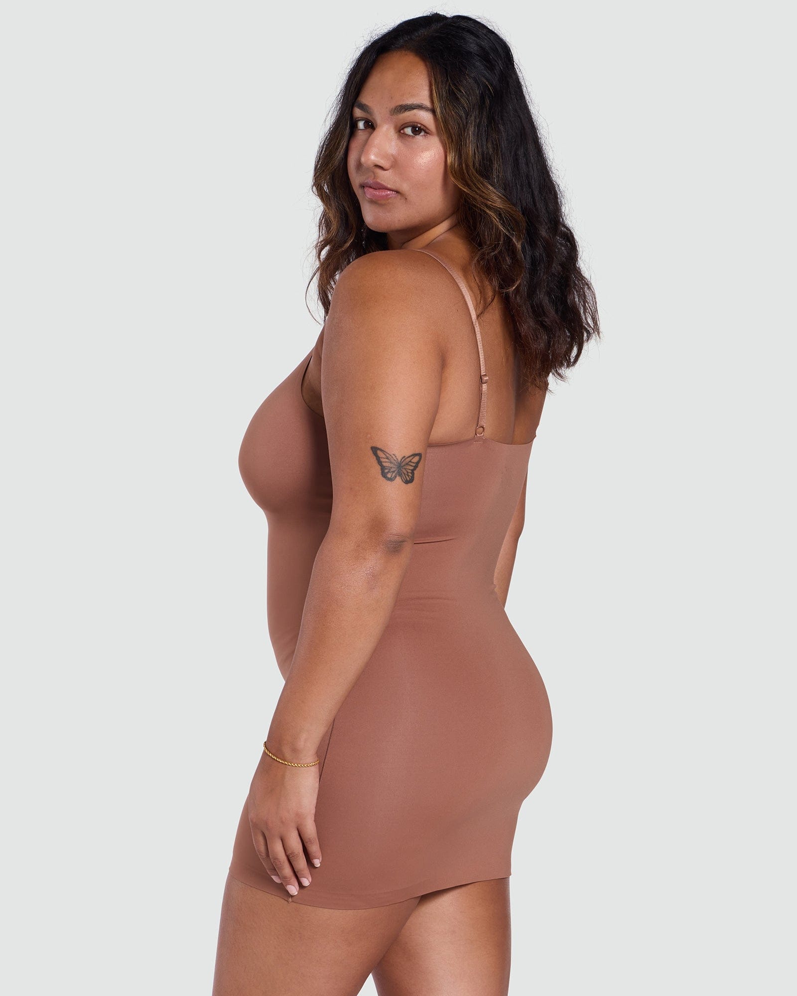 Woman wearing a brown bodysuit against a white background