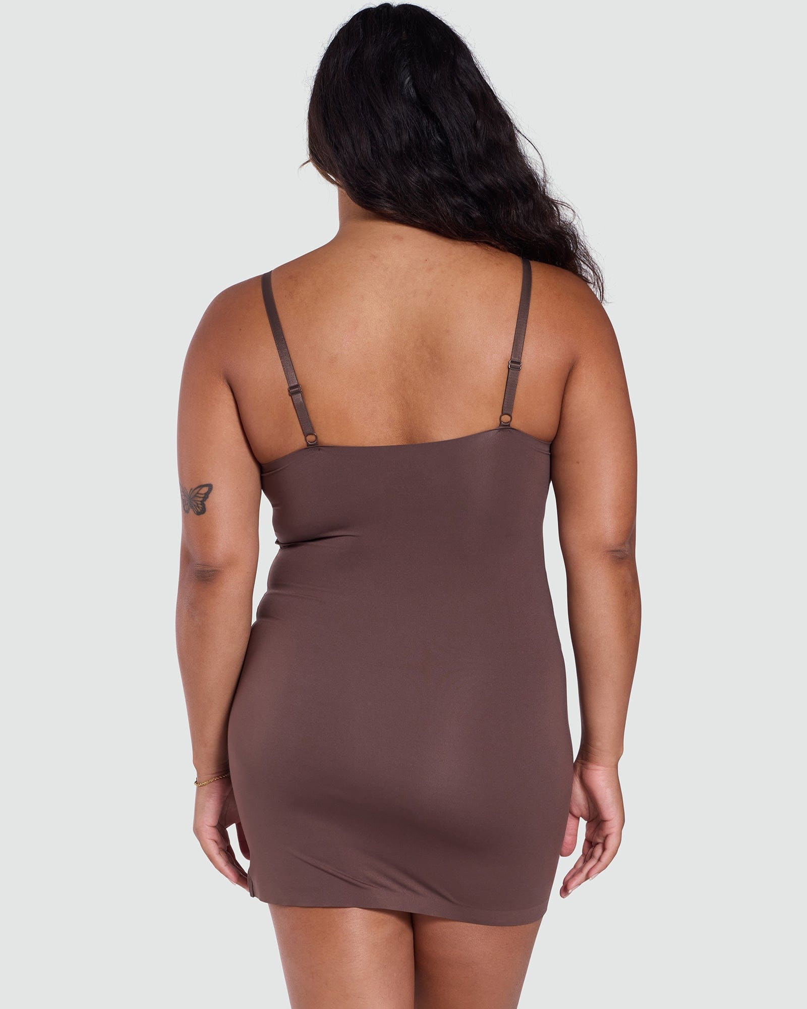 Woman wearing a brown slip dress on a plain background