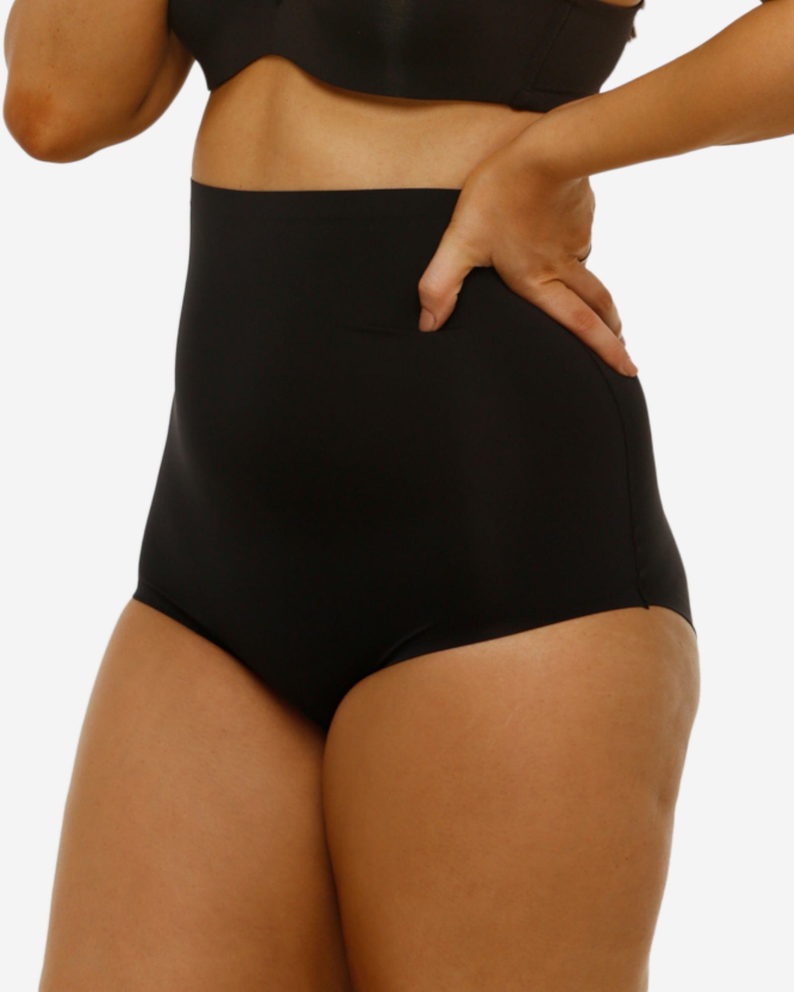 Person wearing black high-waisted underwear on a plain background