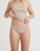 Woman wearing a beige tank top and underwear set on a plain background