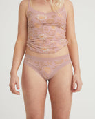 Woman wearing a matching pink floral lingerie set on a plain background