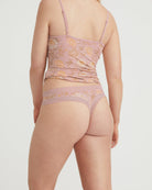 Person wearing a pink lace lingerie set on a plain background