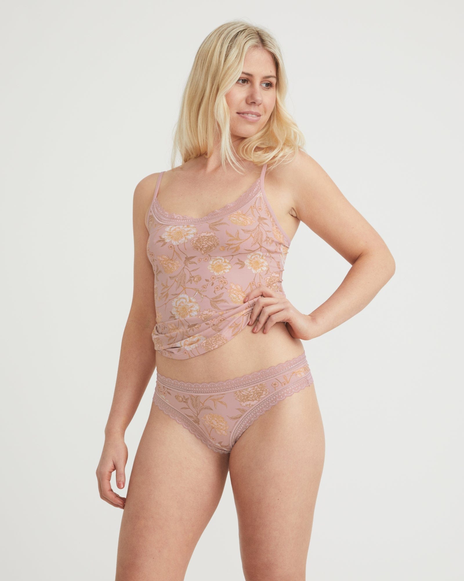 Woman wearing a pink lace lingerie set on a white background