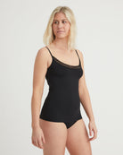 Woman wearing a black bodysuit with lace trim on a white background