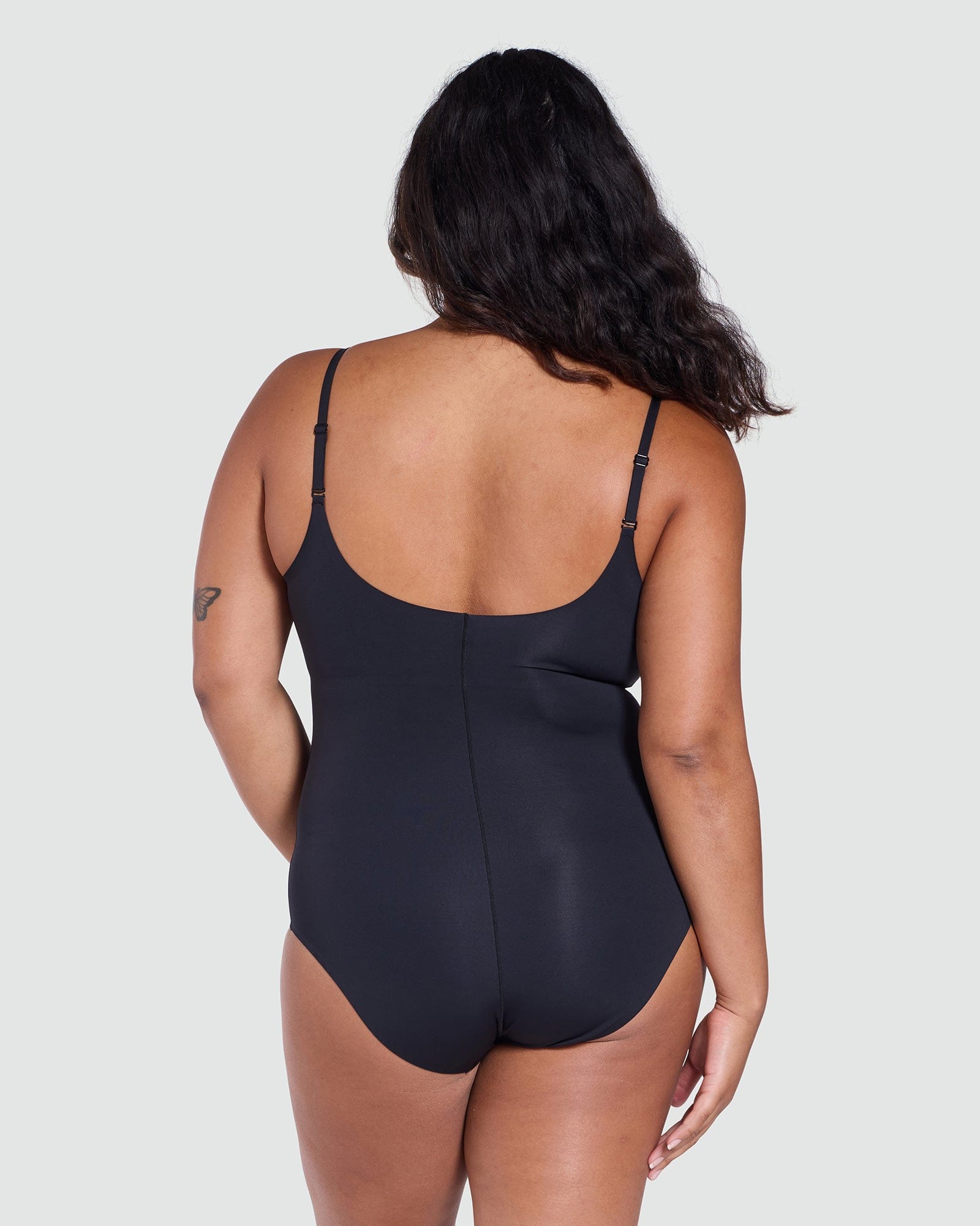 Person wearing a black bodysuit on a light gray background