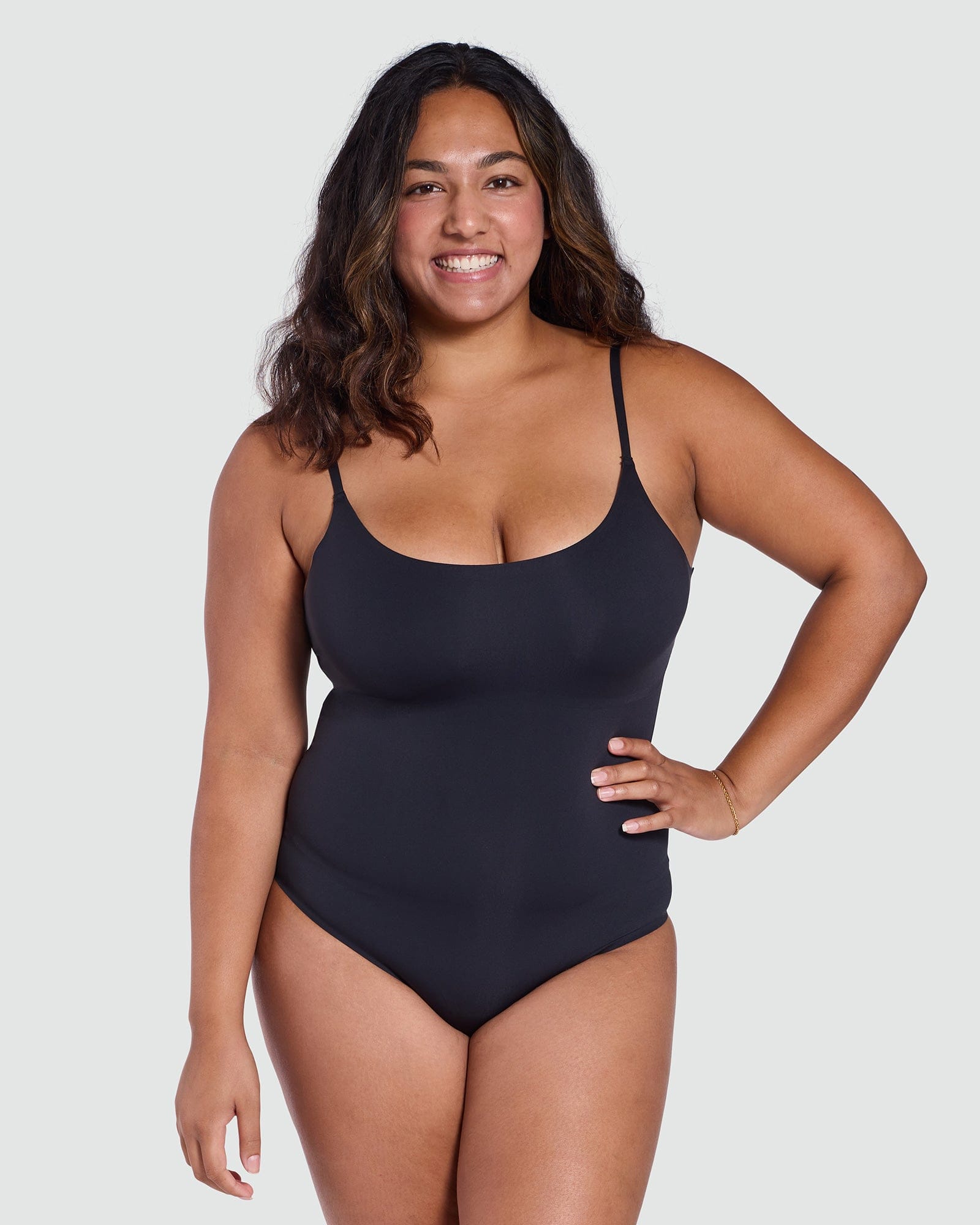 Woman wearing a black bodysuit against a plain background