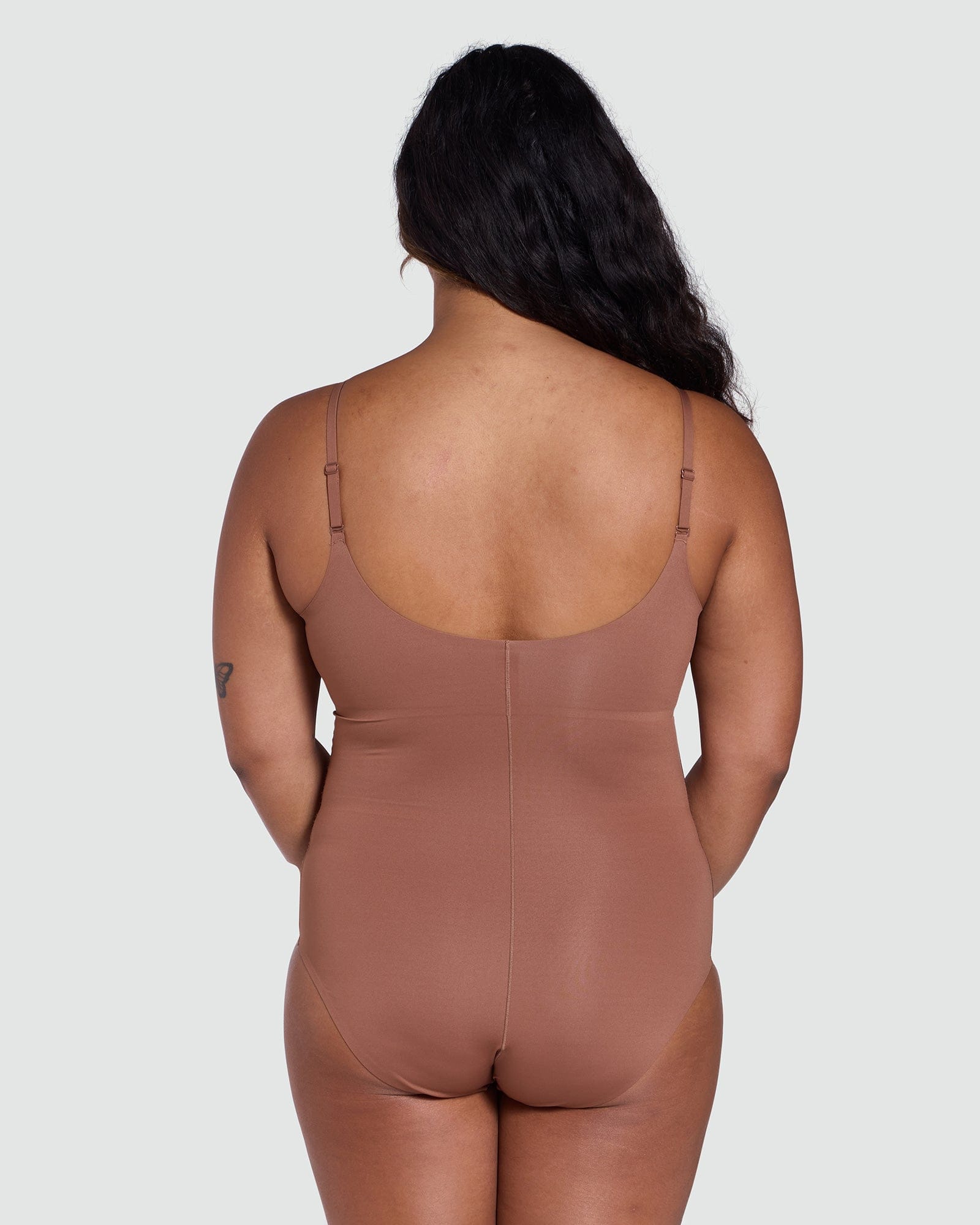 Person wearing a brown bodysuit against a plain background