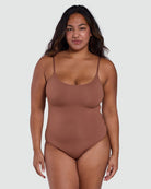 Woman wearing a brown bodysuit against a white background