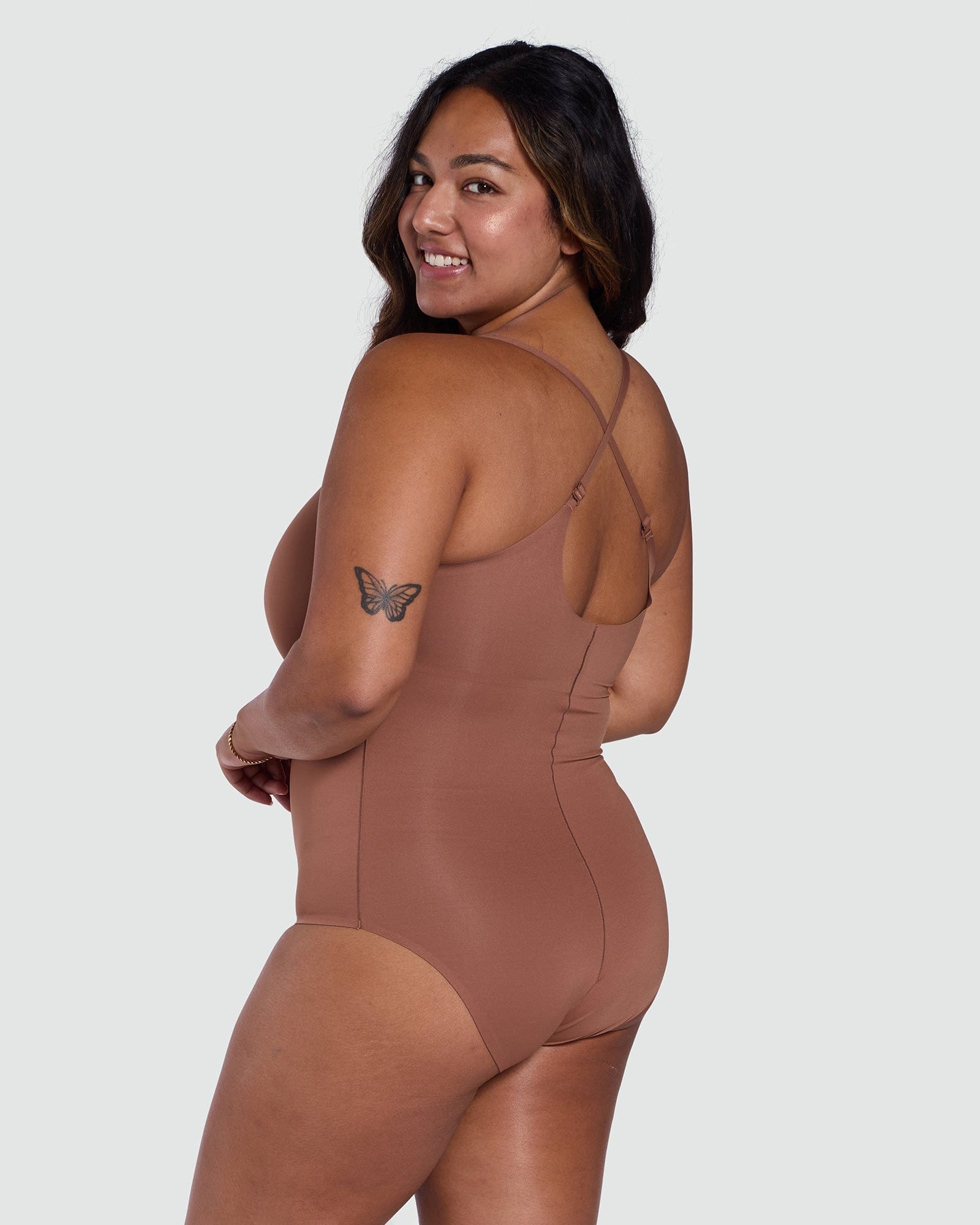 Woman wearing a brown bodysuit on a white background