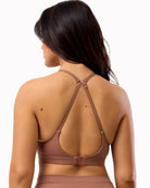 Woman wearing a brown sports bra and leggings on a white background