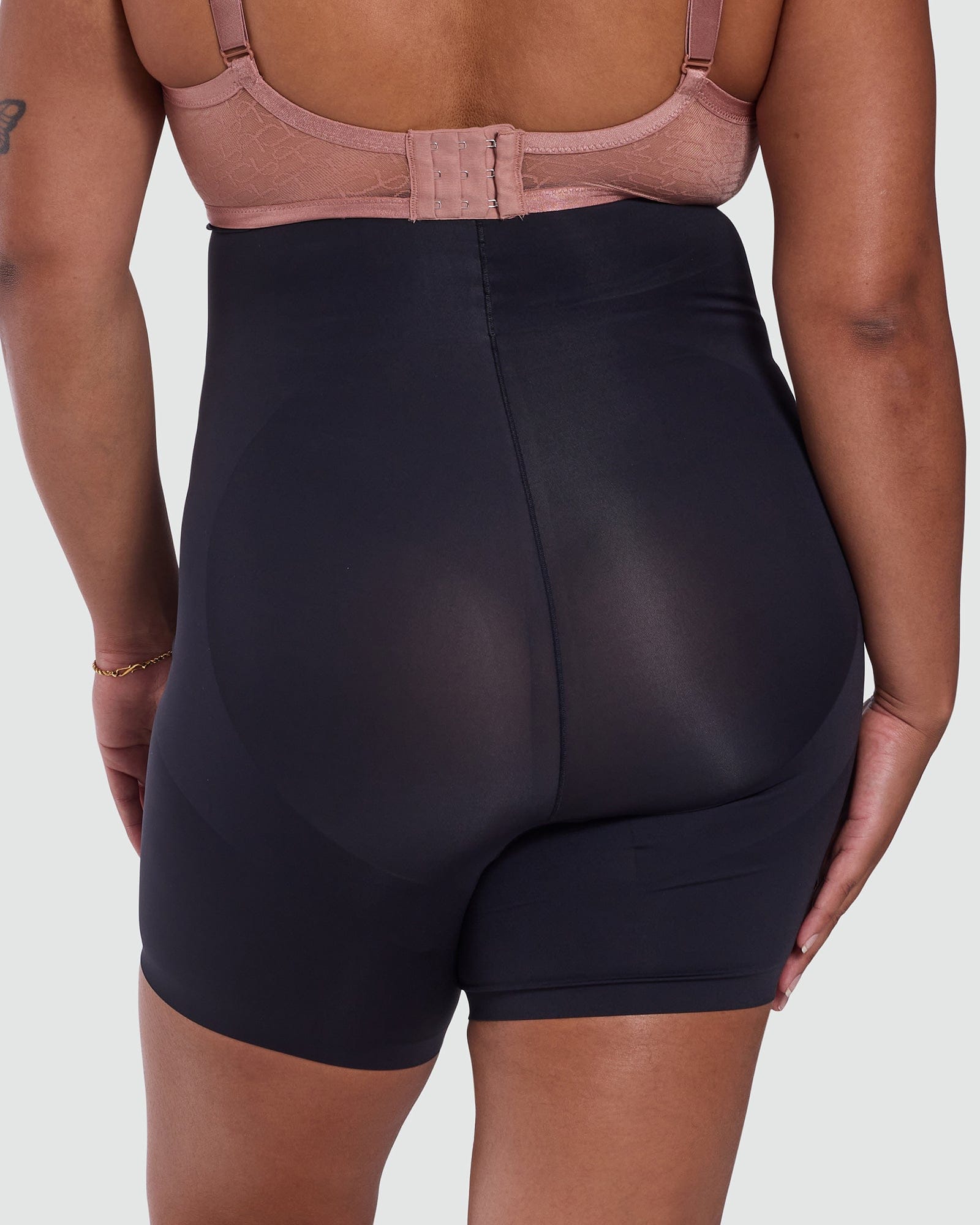 Person wearing black high-waisted shorts and a pink bra on a white background