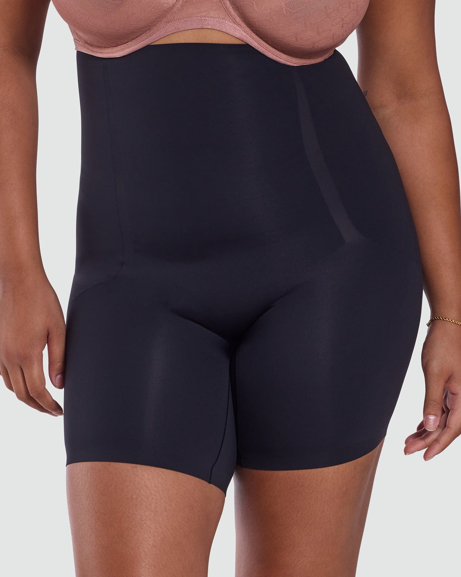 Person wearing black high-waisted shorts on a plain background