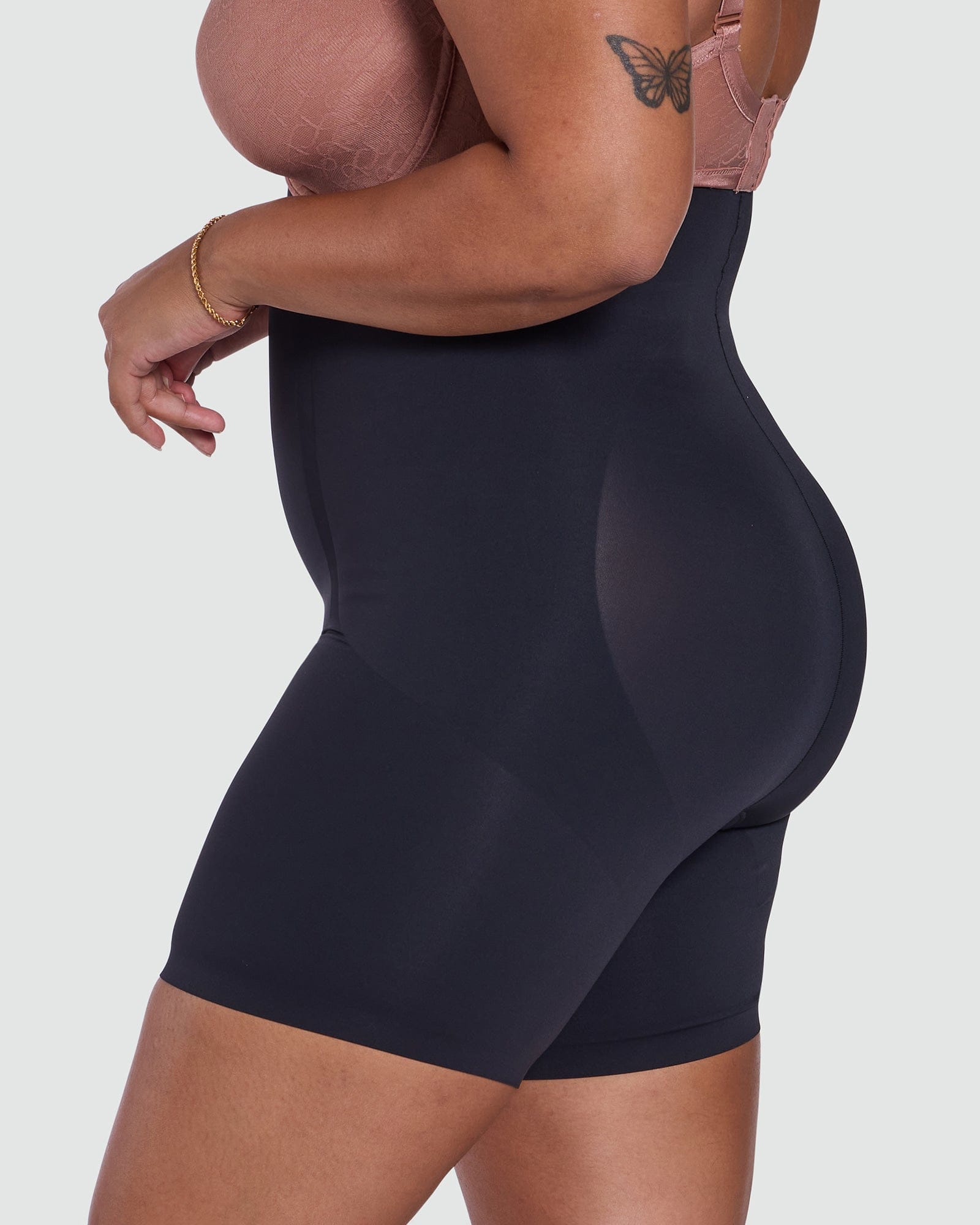 Person wearing a black shapewear garment on a plain background