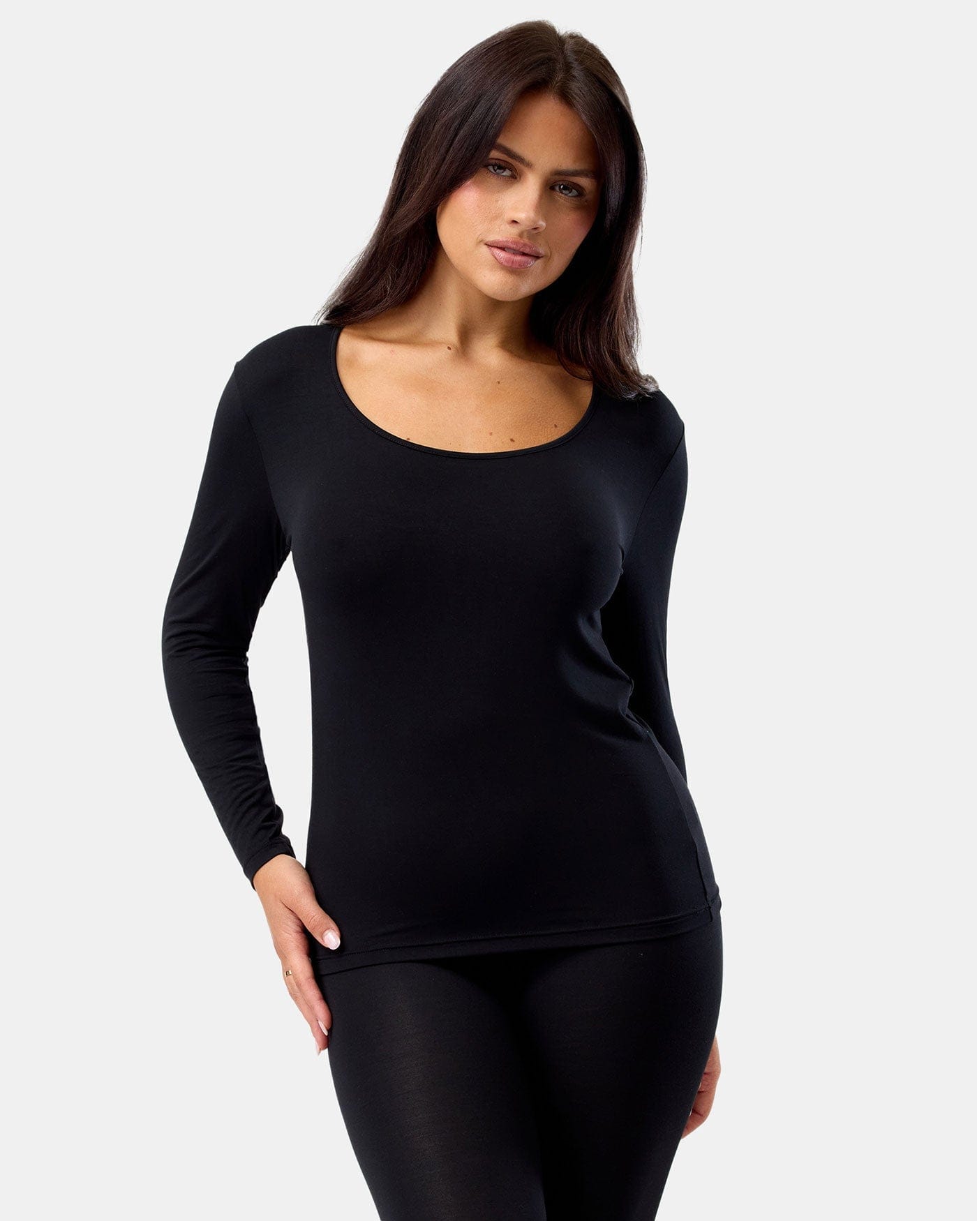 Woman wearing a black long-sleeve top and leggings on a white background