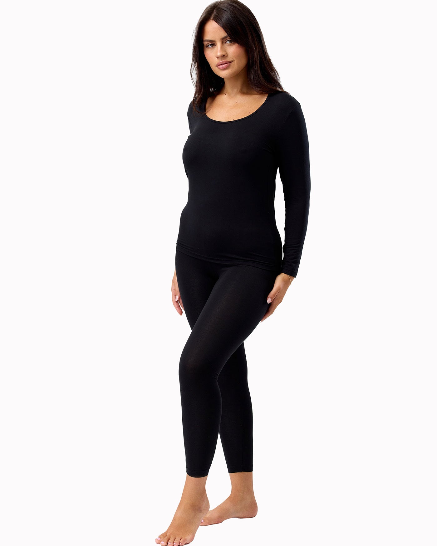 Woman wearing a black long-sleeve top and leggings on a white background