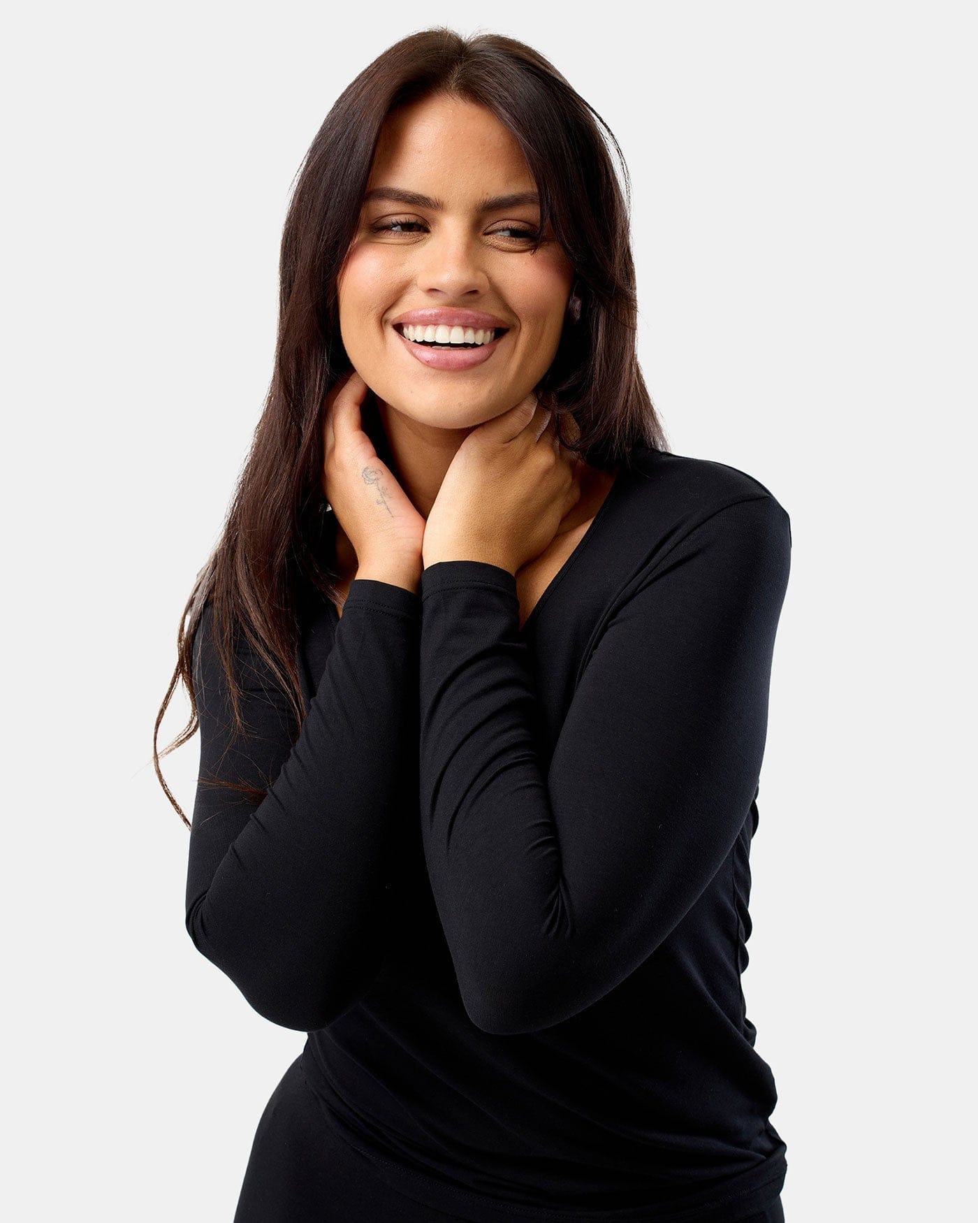 Woman wearing a black long-sleeve top against a plain background