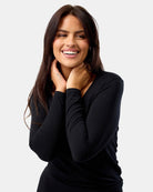 Woman wearing a black long-sleeve top against a plain background