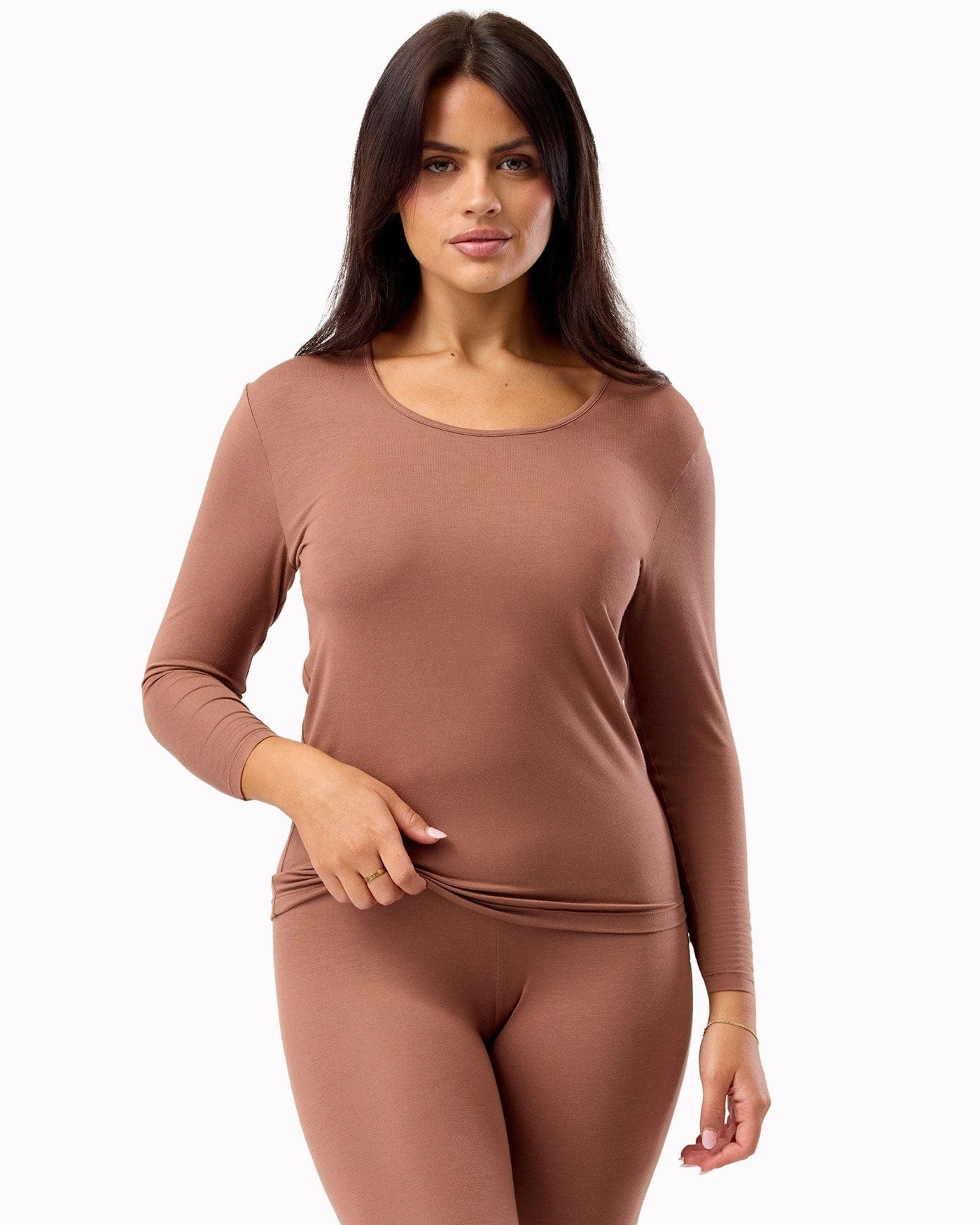 Woman wearing a brown long-sleeve top and leggings on a white background