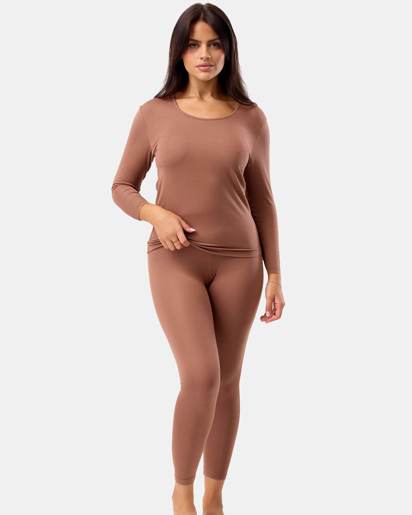 Woman wearing a brown long-sleeve top and leggings on a white background