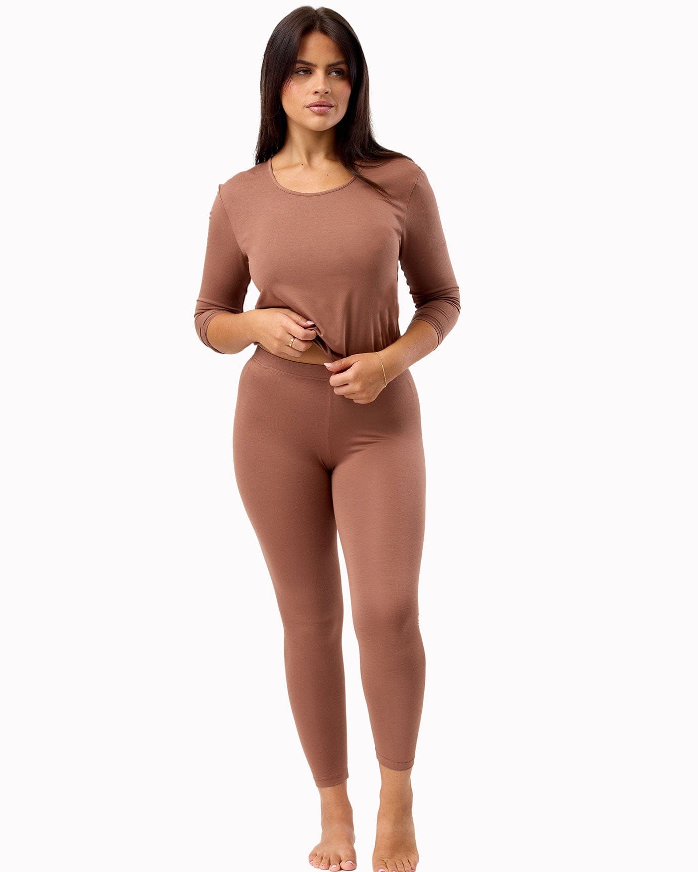 Woman wearing a brown long-sleeve top and leggings on a white background