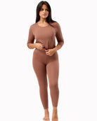 Woman wearing a brown long-sleeve top and leggings on a white background