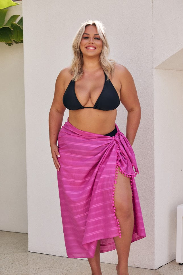 Blonde model wearing black bikini with hot pink sarong