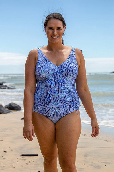 Brunette model wearing blue and white floral v neck ruched tie swimsuit