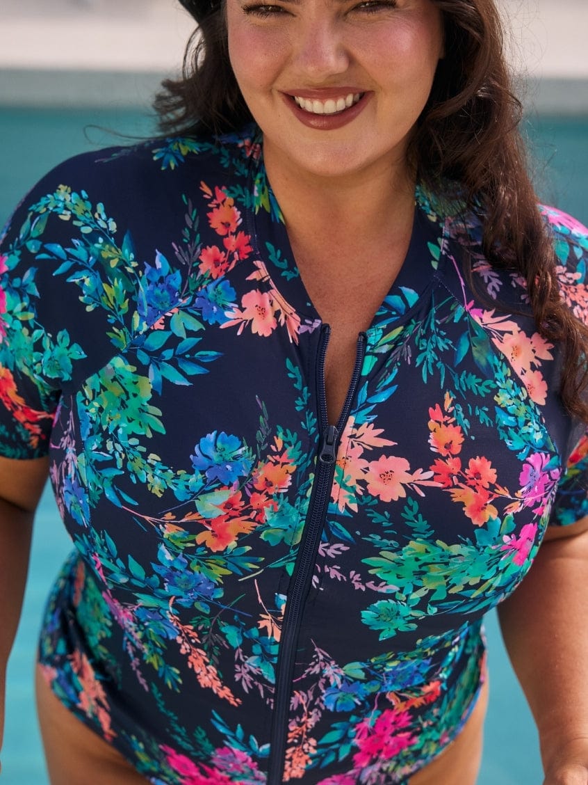 Close up photo of woman wearing a floral rash vest swimsuit.