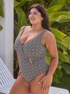 Woman wearing a patterned swimsuit sitting on a chair with greenery in the background