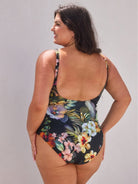 Woman wearing a floral one-piece swimsuit against a plain background