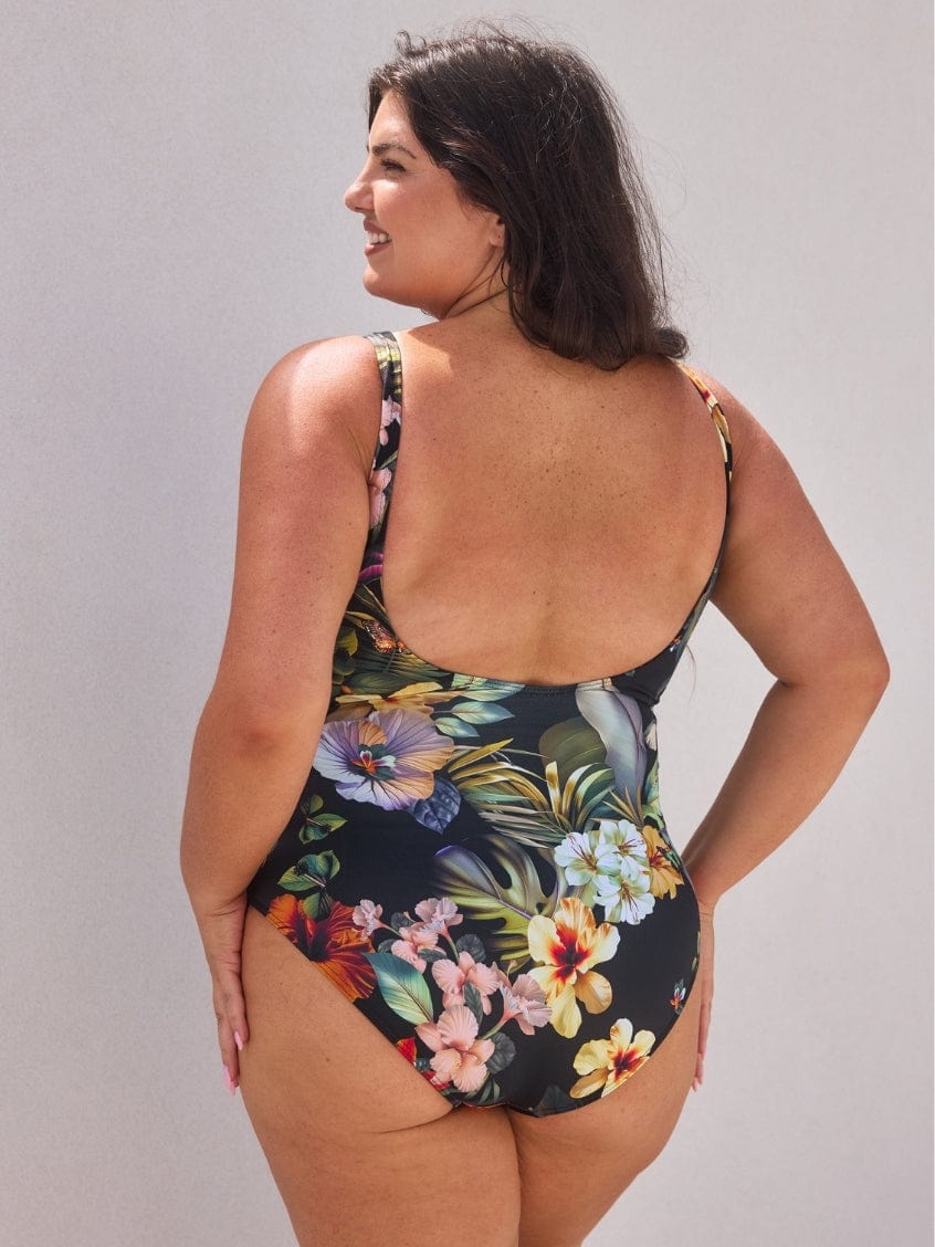 Woman wearing a floral one-piece swimsuit against a plain background