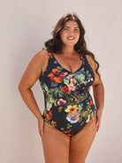 Woman wearing a floral one-piece swimsuit against a plain background