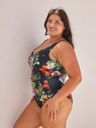 Woman wearing a floral one-piece swimsuit against a plain background