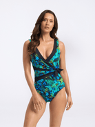 Woman wearing a tropical leaf patterned swimsuit on a white background