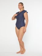 Woman wearing a navy patterned one-piece swimsuit on a white background