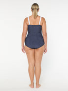 Woman wearing a navy polka dot swimsuit on a white background
