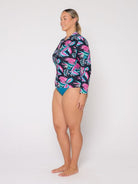 Woman wearing a colorful tropical patterned swimsuit on a white background
