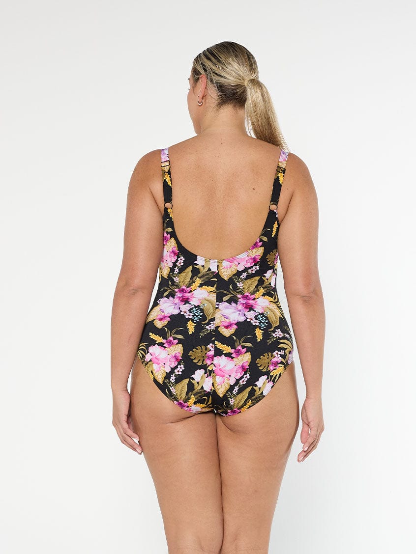 Blonde model wears low scoop back one piece with pink and gold floral chlorine resistant fabric