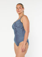 Side profile of model wearing one piece in grey with ruching and criss cross detail