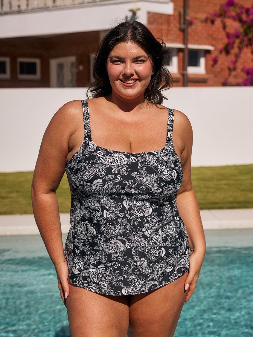 Brunette model standing by pool wearing a chlorine resistant tank tankini top with thick adjustable straps
